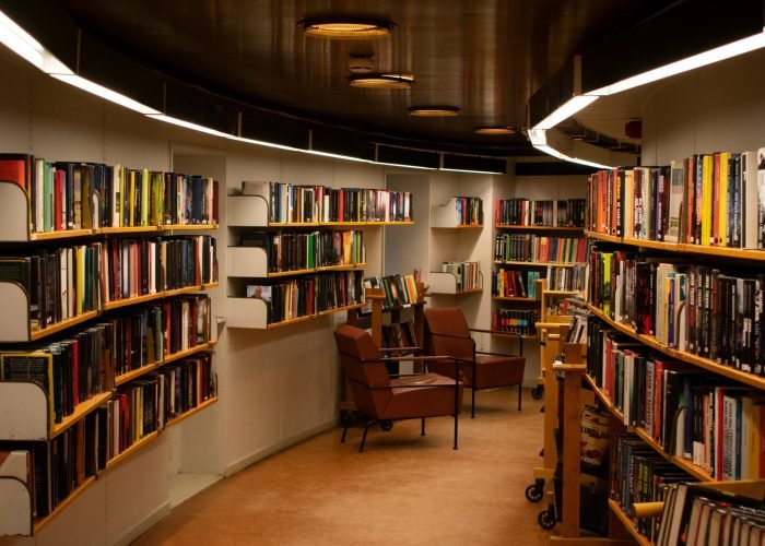 A cozy library space in Stockholm with brown leather chairs and wooden bookshelves filled with books.