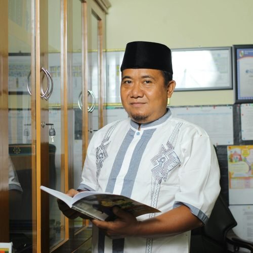 pexels photo 5415445 5415445 A teacher standing in an office in Indonesia, holding a book, conveying education.